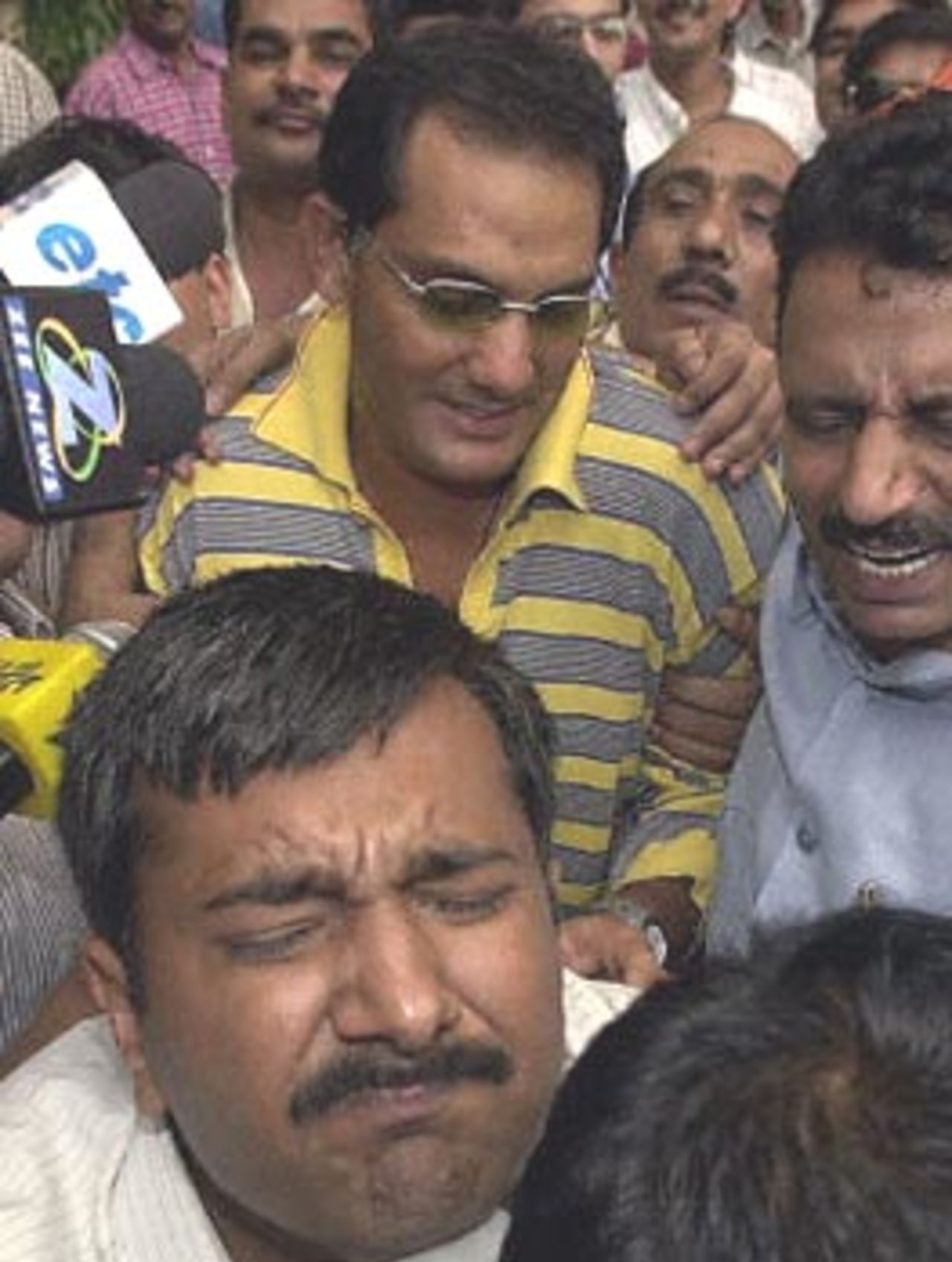 Central Bureau of Investigation (CBI) agents make a way through a crowd of reporters for former India cricket captain Mohammad Azharuddin (C) as he leaves the CBI 22 June 2000. Azharuddin was brought in for questioning after disgraced South African captain Hansie Cronje named him in a case of match fixing.