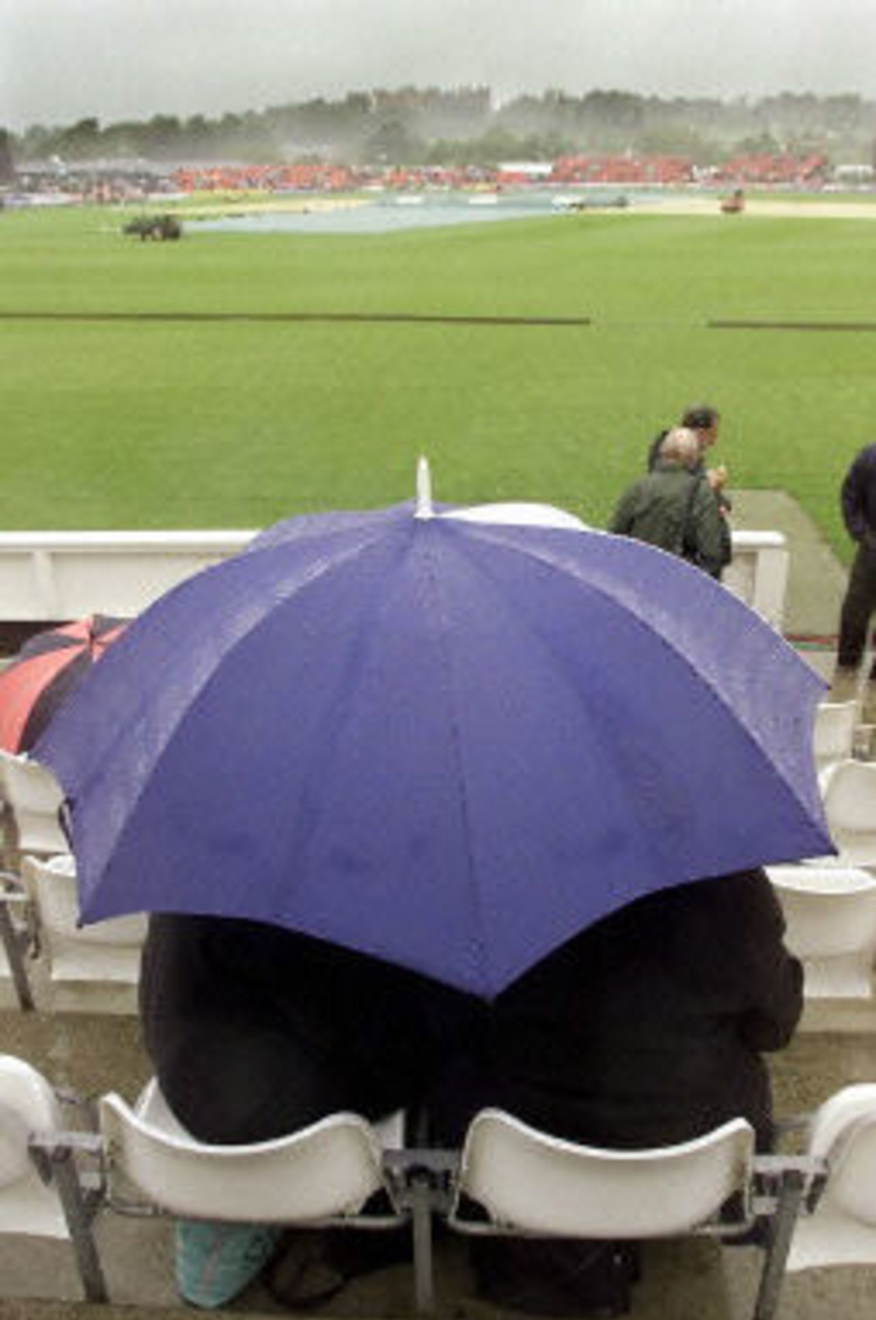 Cricket fans sit in the driving rain which has delayed the start of the Australia v Pakistan one-day game, 6th ODI at Chester-le-Street, 16 June 2001.