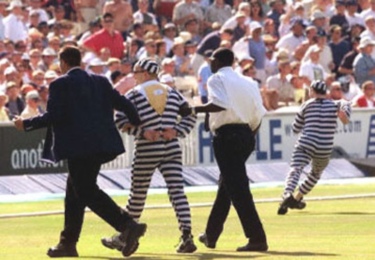 A pitch invader dressed as a jailbird is escorted from the ground as his comrade dashes away, 9th ODI at the Oval, 21 June 2001.