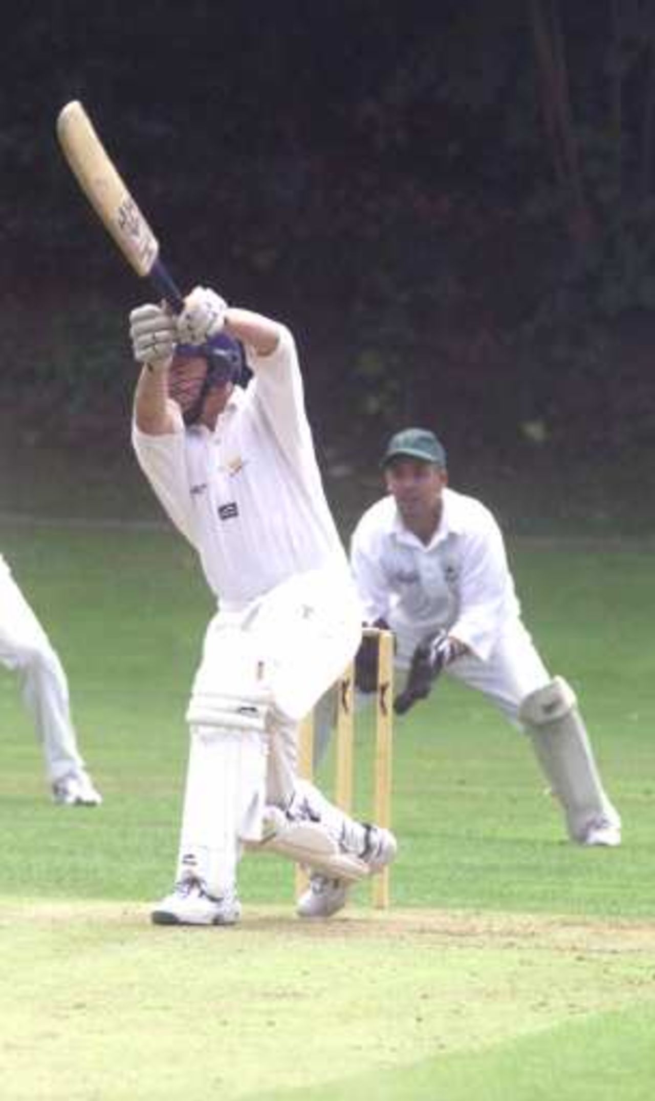 Richard Kenway of BAT CC hits out in his innings of 99 against Calmore CC, wicket-keeper Stuart Bailey looks on