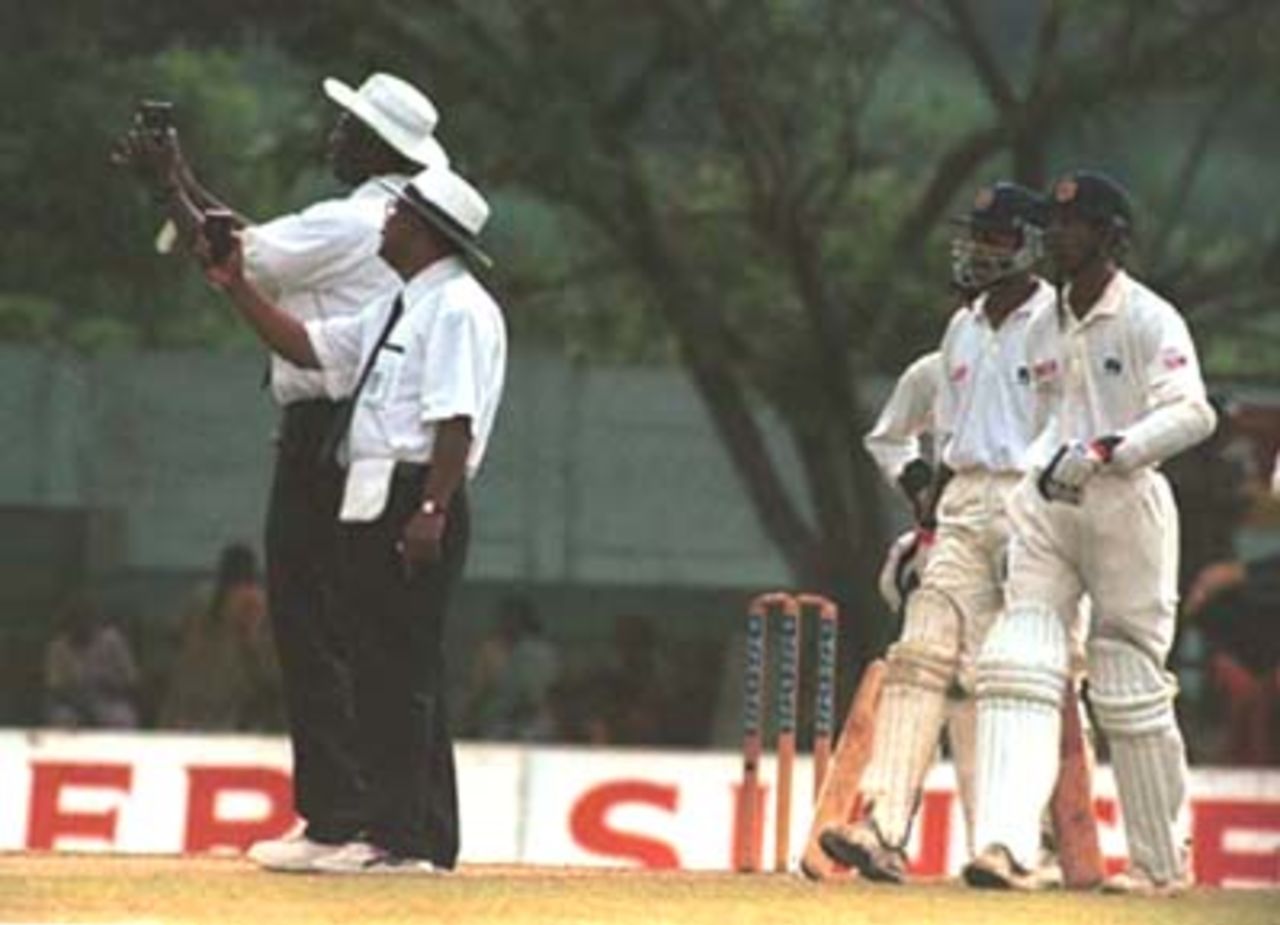 The umpires measure the light conditions as batsman Marvan Atapattu and Kumar Dharmasena look on during the third day of the third cricket Test between Sri Lanka and Pakistan in Asgiriya International cricket stadium in Kandy, Sri Lanka on Friday, June. 30, 2000