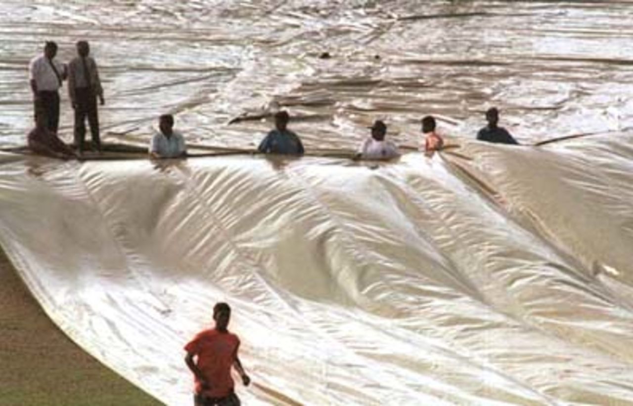 Ground staff collect water from the pitch covers during the fourth day of the third and final cricket Test between Sri Lanka and Pakistan in Asgiriya International cricket stadium in Kandy, Sri Lanka on Saturday, July.1, 2000