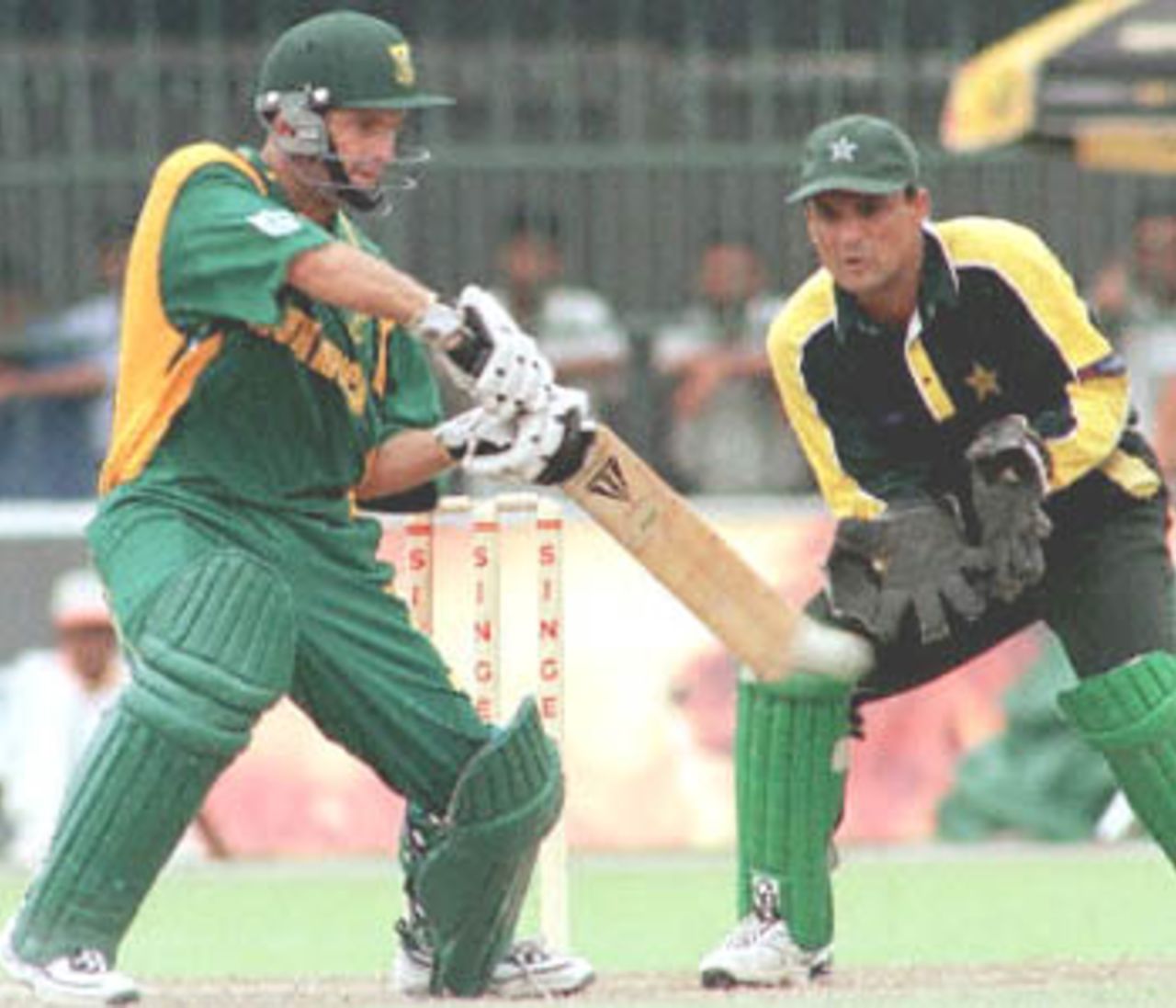 South African batsman Gary Kirsten cuts the ball in his innings of 52 in the day-night limited overs match against Pakistan in the Singer Cup triangular. Pakistan skipper Moin Khan looks on. Pakistan have been set a target of 242 to win. Singer Triangular Series, 2000, 3rd Match, Pakistan v South Africa, R.Premadasa Stadium, Khettarama, Colombo, 8 July 2000.