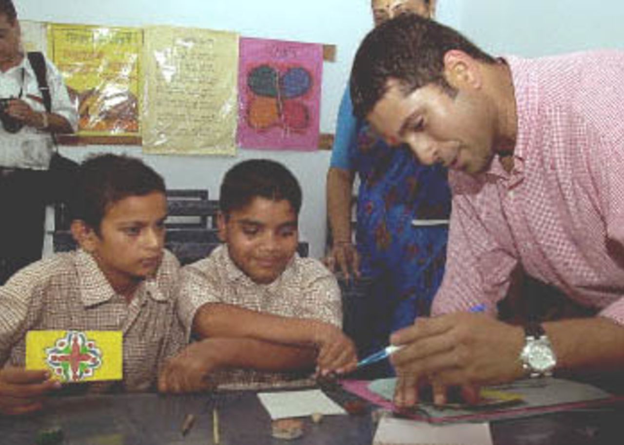 Indian cricket star Sachin Tendulkar (R) signs autographs for physically challenged children at the Akshay Pratishtan Vocational Training Centre, 14 July 2000. Tendulkar inaugurated the center, a social service project undertaken by the Rotary Club of Delhi South-end, which provides vocational training to physically handicapped children.