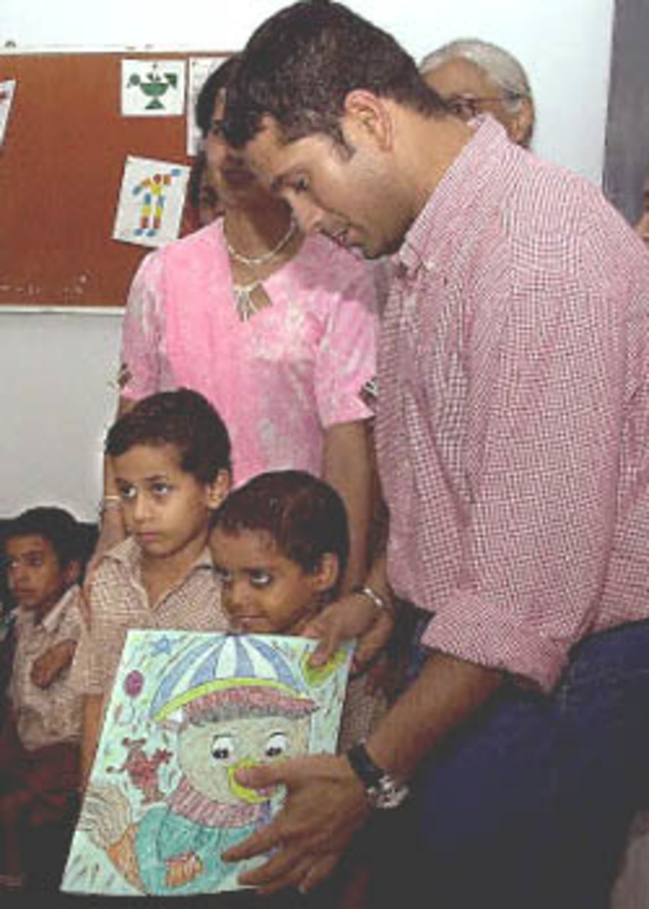 Indian cricket star Sachin Tendulkar (R) poses with a drawing given to him by a physically challenged child at the Akshay Pratishtan Vocational Training Centre, 14 July 2000. Tendulkar inaugurated the center, a social service project undertaken by the Rotary Club of Delhi South-end, which provides vocational training to physically handicapped children.
