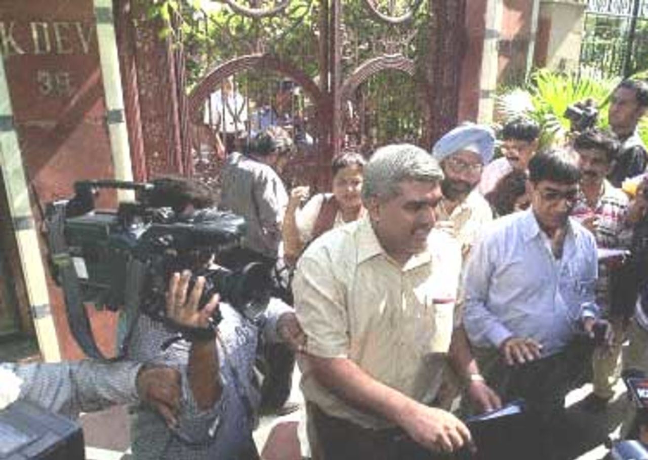 An unidentified senior income tax official (2nd L, next to cameraman) is mobbed by reporters as he leaves the residence of Indian cricket coach and former captain Kapil Dev following a raid by income tax officials. Tax officials have raided the homes of top Indian cricket players around the country, threatening a fresh scandal in a sport already laid low by match-fixing charges.