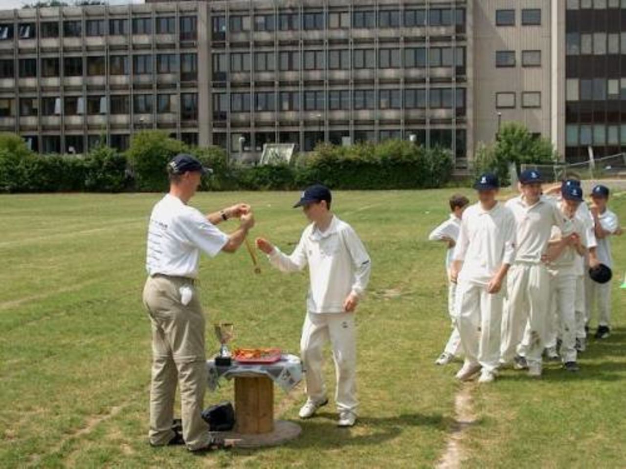 The winning British School Brussels Under-13 team lines up to receive their finalists medal and the Cricket Belgium U13 Trophy from Paul Larivière