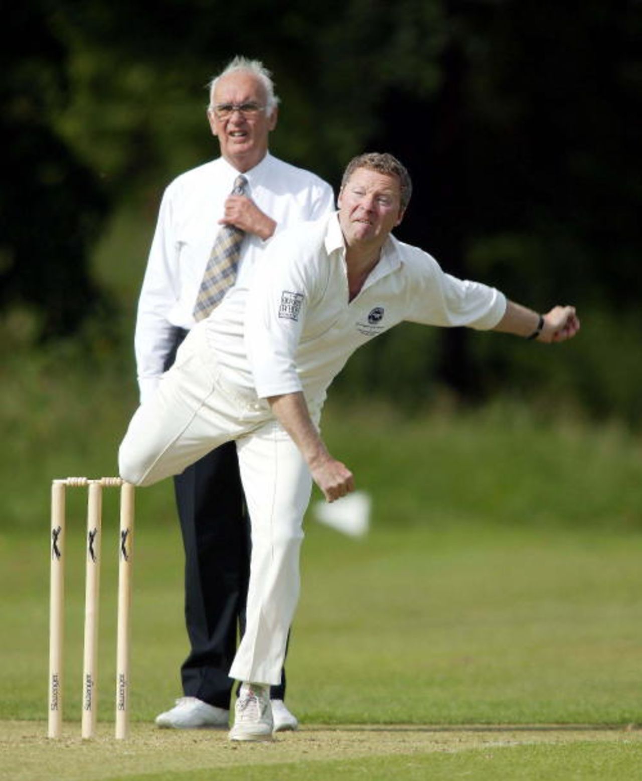 Rory Bremner puts his back into his bowling, Umpire Terry Brewer looks on