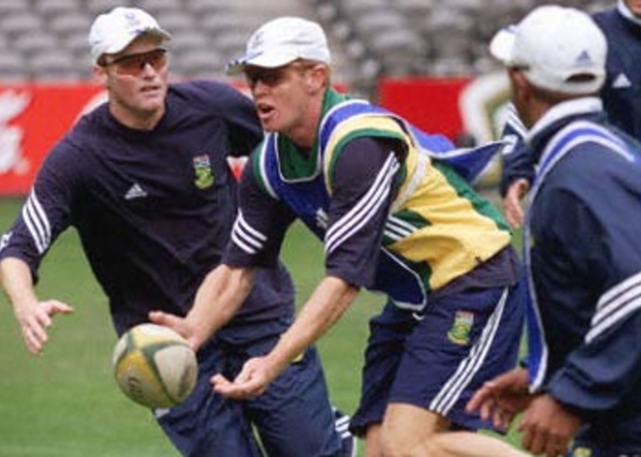 South African skipper Shaun Pollock (C) gets a pass away in a game of touch rugby before practising under the closed roof of the Colonial Stadium in Melbourne (14 August 2000). Australia and South Africa will create history when play the first one-day cricket matches to be played indoors when they meet on 16, 18 and 20 August. Others in the picture unidentified. Super Challenge 2000.