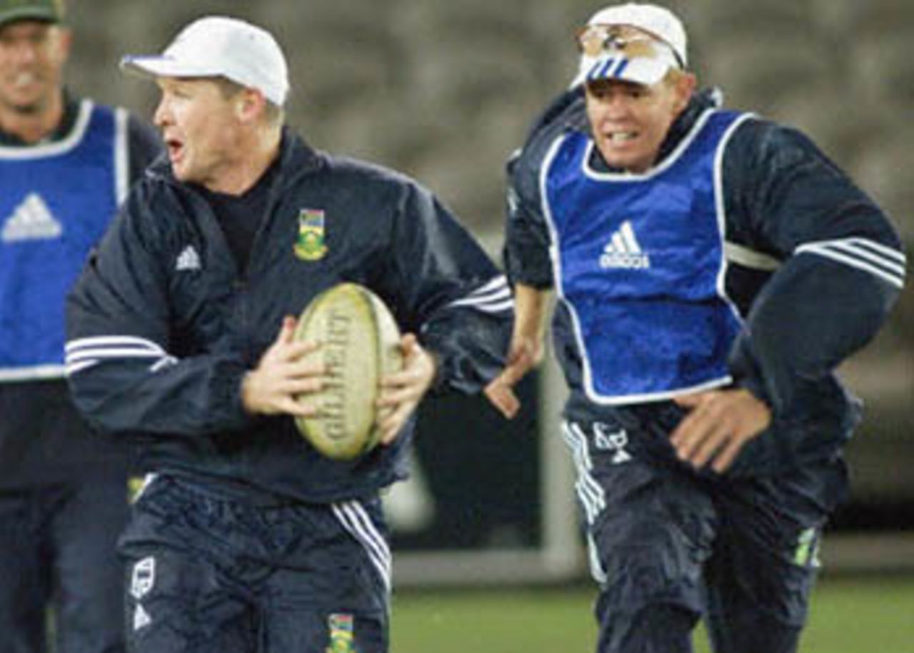 South African captain Shaun Pollock (R) prepares to tackle an unsuspecting Daryll Cullinan (C) (15 August 2000 during a lighter moment in training in preparation for the Australia versus South Africa match that will played under the closed roof of the Colonial Stadium in Melbourne. Australia and South Africa will create history when they play the first one-day cricket matches indoors 16, 18 and 20 August. Super Challenge 2000.