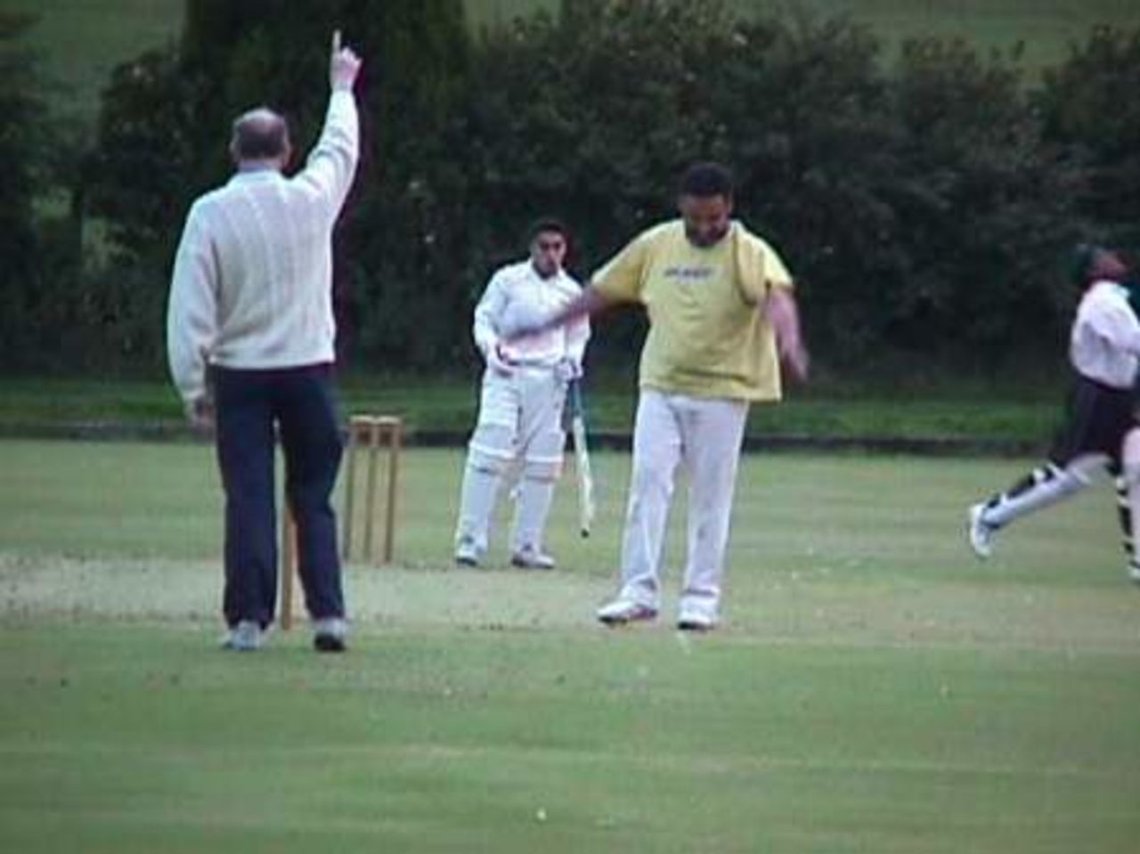 Umpire Brian Rutter's raised finger signals the dismissal of Khizer Rehman, caught by wicketkeeper Abrar Shah