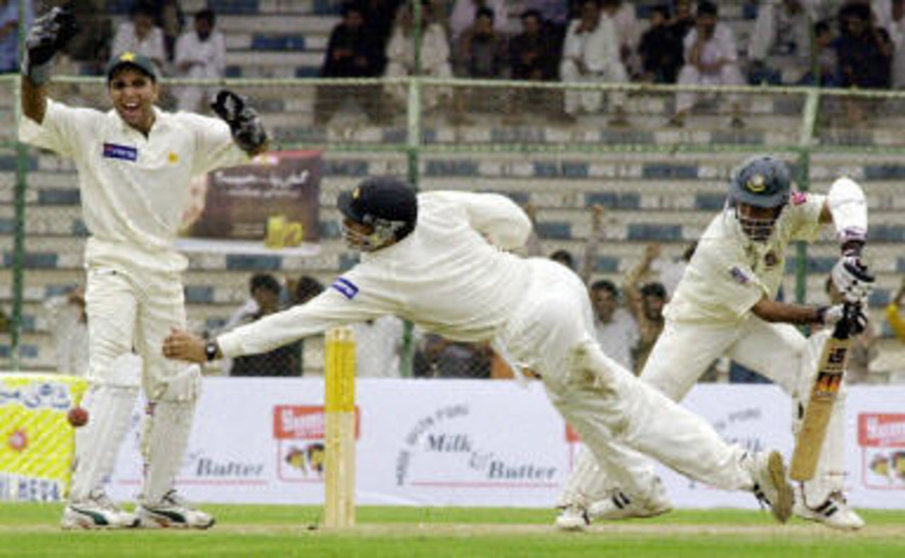 Bangladesh batsman Khaled Mashud (R) gets the ball past a lunging Yasir Hameed (C) as stand-in wicketkeeper Taufeeq Umar (L) looks on, opening day of the first Test at the National Stadium in Karachi, 20 August 2003.