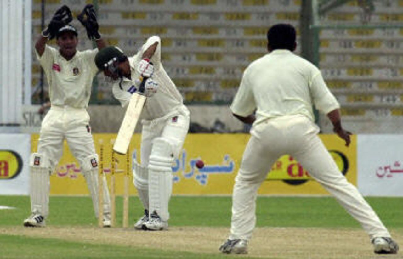 Shoaib Akhtar (C) clean bowled by Mohammad Rafique (R) as wicketkeeper Khaled Mashud (L) looks on during the third day of the first Test match between Pakistan and Bangladesh in Karachi, 22 August 2003.