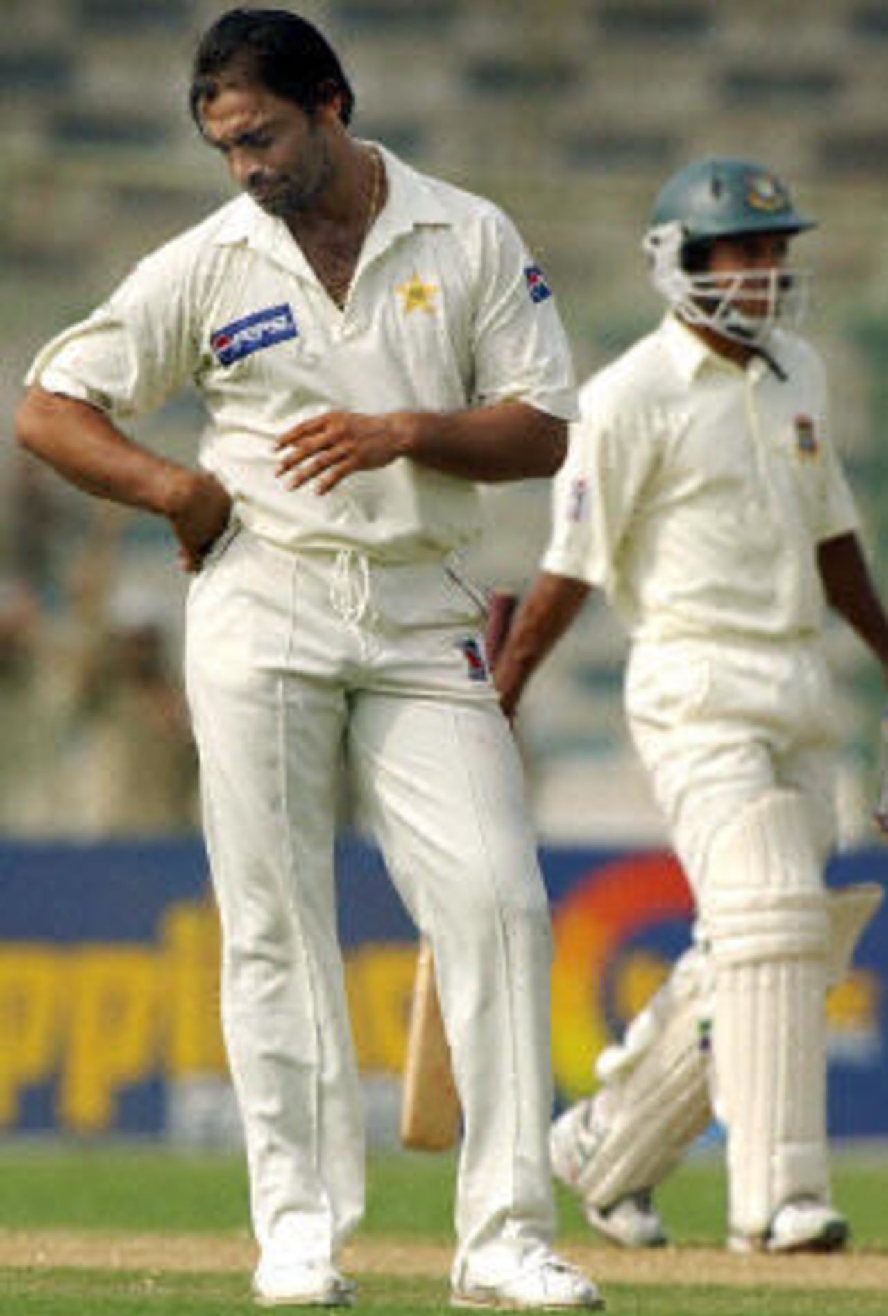 Shoaib Akhtar (L) looks downcast as Habibul Bashar (L) walks by during the third day of the first Test match between Pakistan and Bangladesh in Karachi, 22 August 2003.