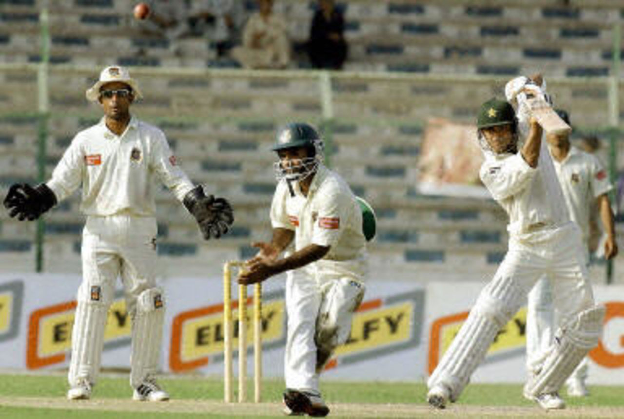 Yasir Hameed (R) hits a ball as wicketkeeper Khaled Mashud (L) and fielder Sanwar Hossain (C) look on during the fourth day of the first Test match between Pakistan and Bangladesh in Karachi, 23 August 2003.