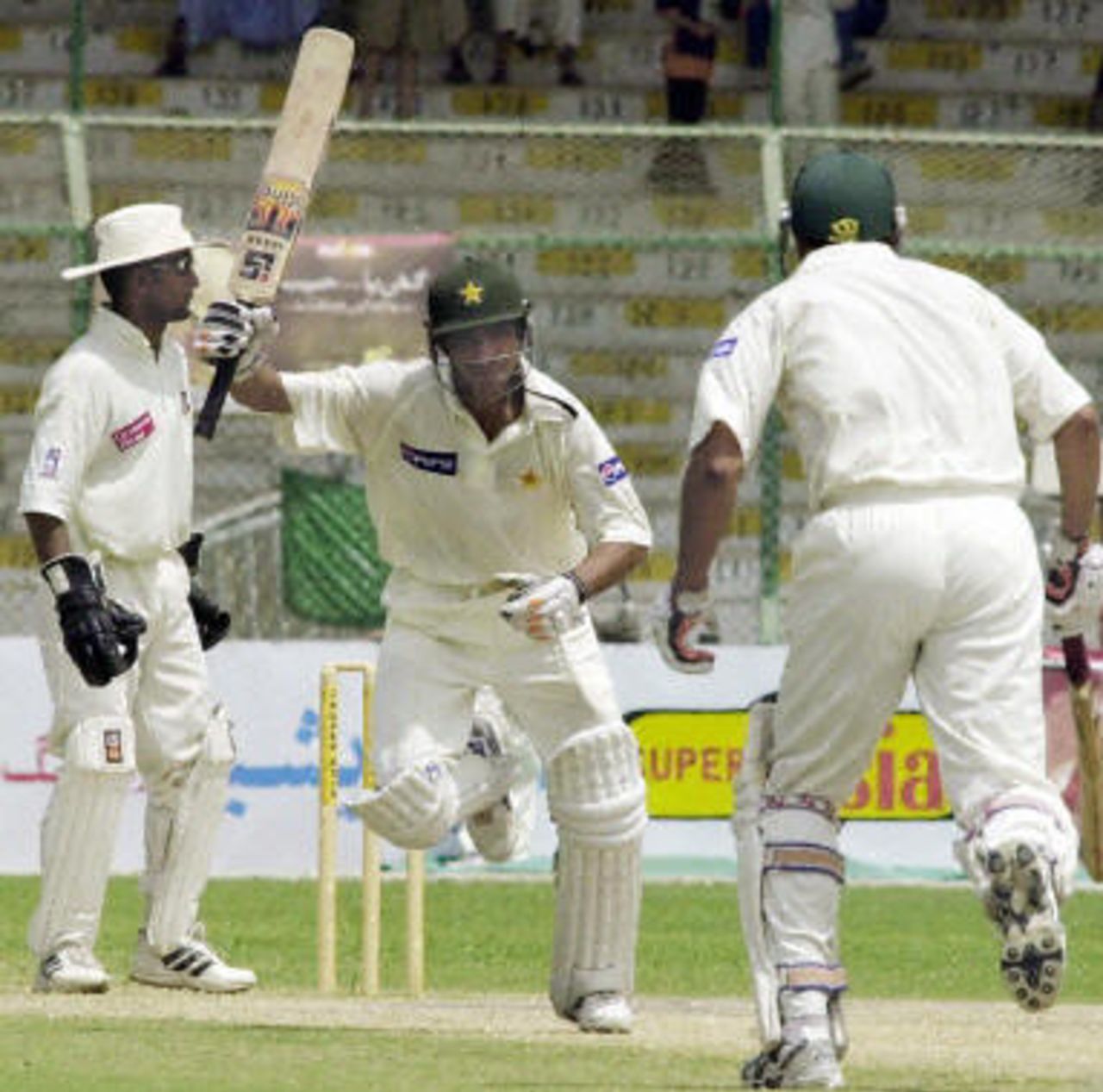 Yasir Hameed (C) raises his bat as he celebrates completing his second century during the first Test match between Pakistan and Bangladesh in Karachi, 24 August 2003. Yasir Hameed became only the second batsman in Test cricket to hit two hundreds in his debut Test.