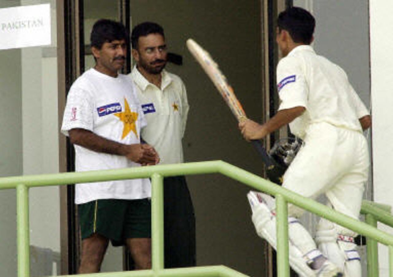 Yasir Hameed (R) is congratulated by coach Javed Miandad (L) and the team doctor as he walks into the dressing room, after scoring his second century during the last day play of the first Test match between Pakistan and Bangladesh in Karachi, 24 August 2003.