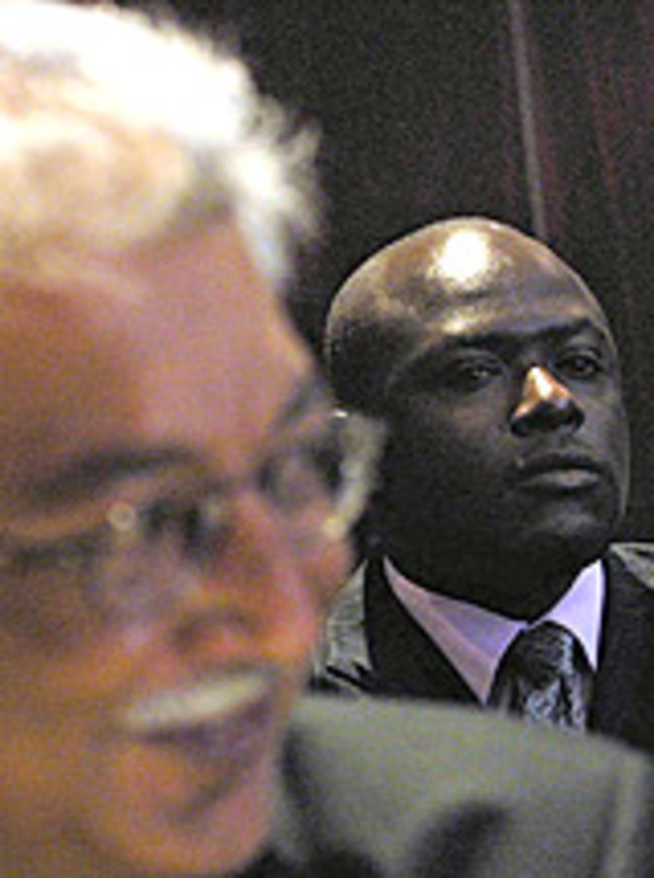 Maurice Odumbe stands behind his lawyer, 27 July, 2004