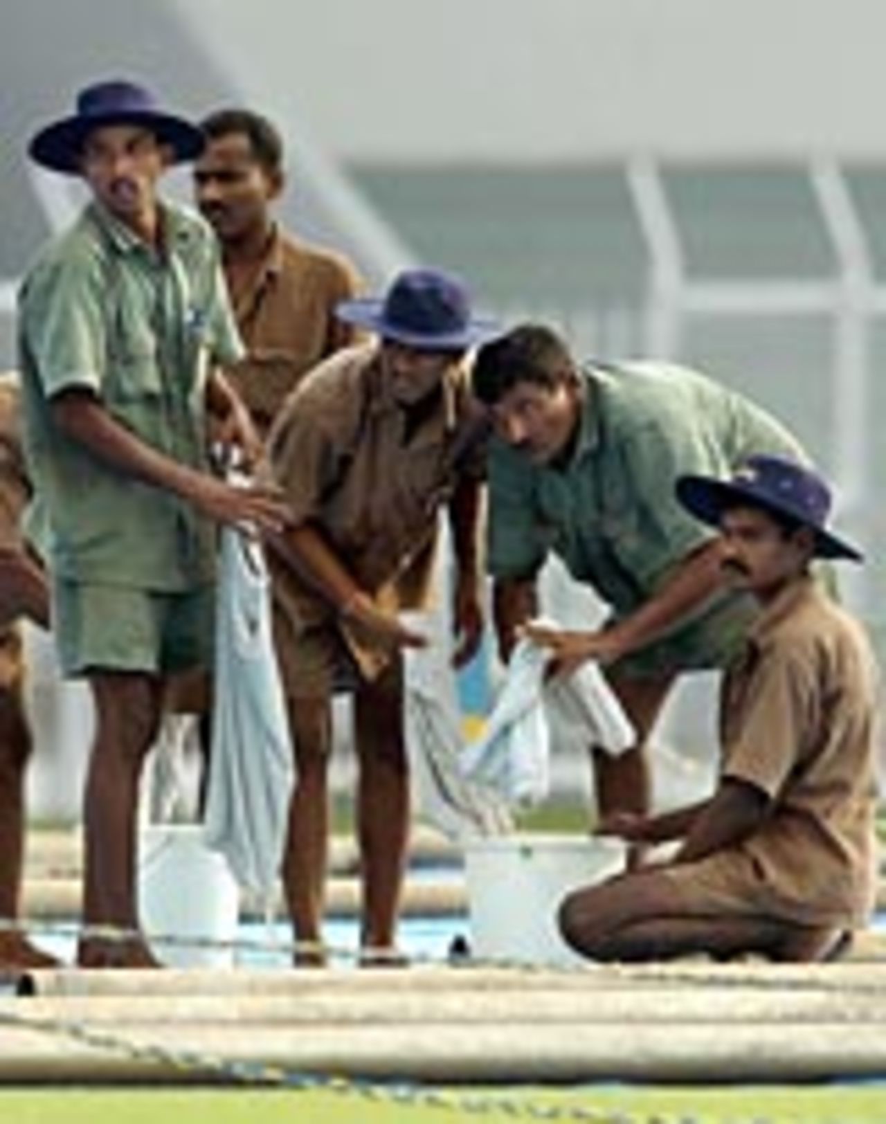 Groundstaff mop-up the wicket before play can start between Australia and Mumbai Ranji at Brabourne stadium, Mumbai, September 30, 2004