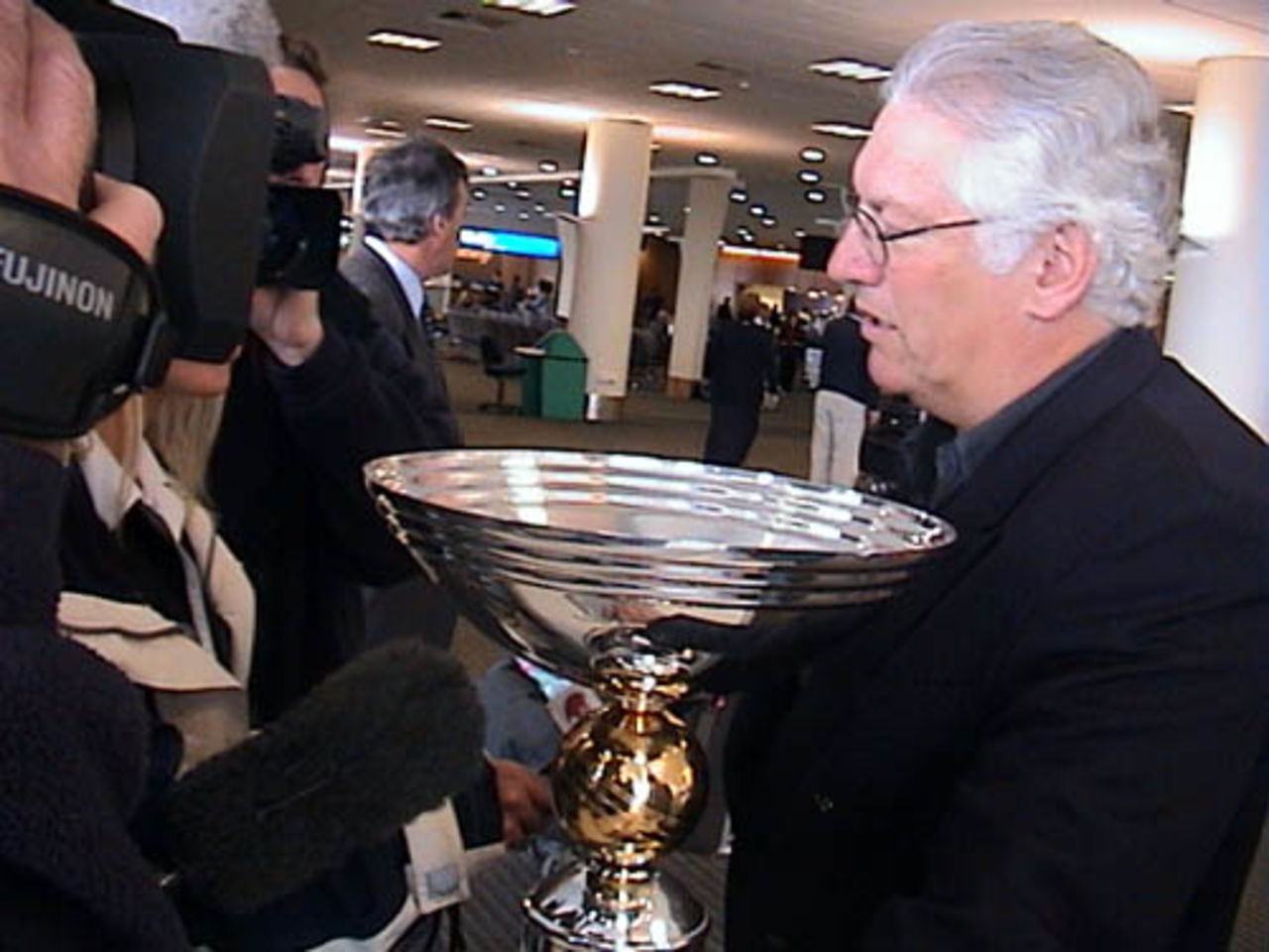 New Zealand Cricket chief executive Christopher Doig, holding the ICC KnockOut trophy, is interviewed by television news crews upon arrival from Nairobi at Christchurch International Airport, 18 October 2000. New Zealand defeated India in the final on Monday 15 October 2000.