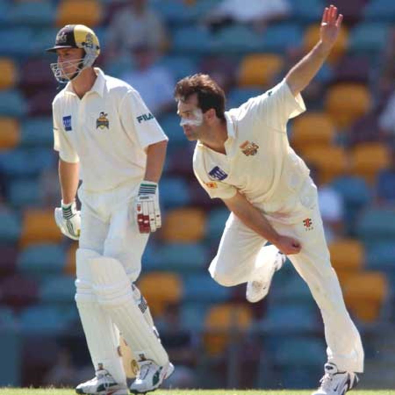18 Oct 2001: Adam Dale of Queensland in action bowling while Adam Gilchrist of Western Australia looks on during the Pura Cup cricket match between Queensland and Western Australia which is being played at the Gabba in Brisbane, Australia.