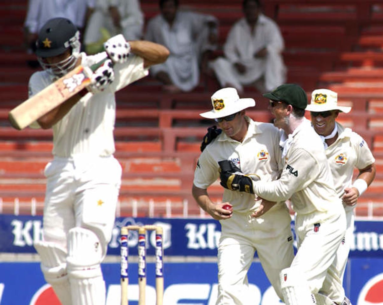 Australia's Mark Waugh (2nd L) is hugged by team mate Adam Gilchrist as Shane Warne (R) follows, after Waugh caught Pakistan vice captain Younis Khan (L) at Sharjah's stadium October 11, 2002 on the first day of their second cricket test. The second and third tests are being held in the neutral venue of Sharjah after Australia balked at playing in Pakistan due to security concerns.