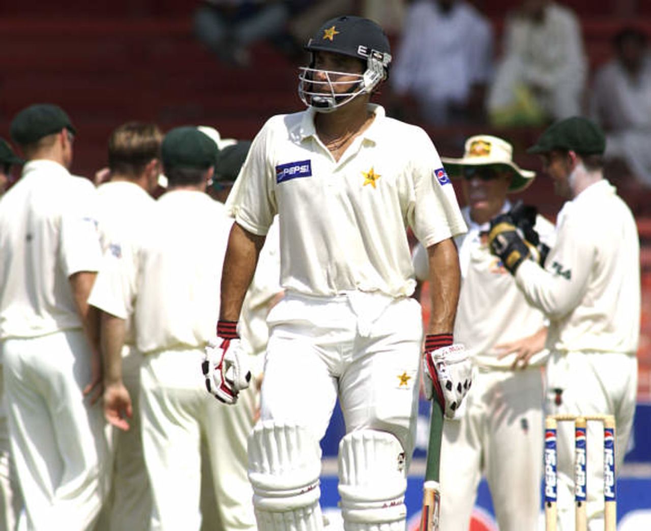 Pakistan's Misbah-ul-Haq (C) walks off after being caught at second slip by Australia's Mark Waugh in Sharjah's stadium October 11, 2002 at the start of their second cricket test match. Pakistan were dismissed for 59 in their first innings, their lowest ever test innings score. The second and third tests are being held in the neutral venue of Sharjah after Australia balked at playing in Pakistan due to security concerns.