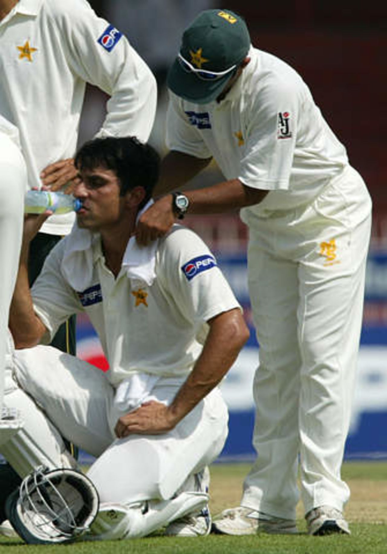 Pakistan's Misbah-ul-Haq (L) is cooled off with a wet towel by a team trainer before being caught at second slip by Australia's Mark Waugh in Sharjah's stadium October 11, 2002 at the start of their second cricket test match. Pakistan were dismissed for 59 in their first innings, their lowest ever test innings score. The second and third tests are being held in the neutral venue of Sharjah after Australia balked at playing in Pakistan due to security concerns.