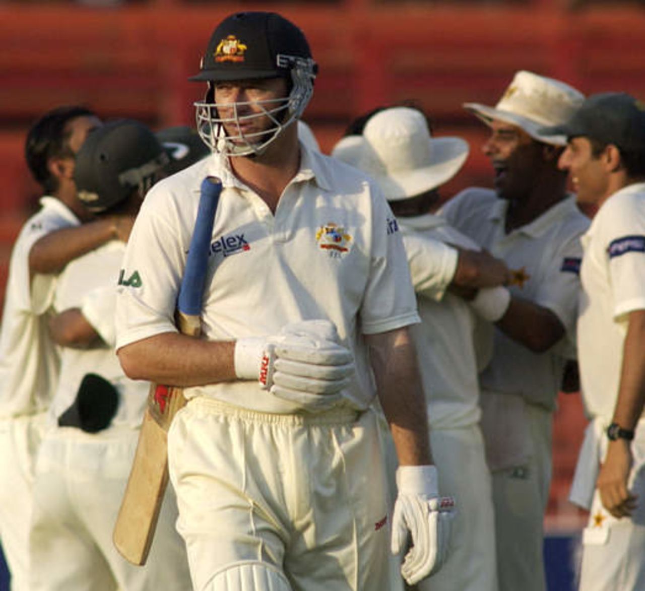 Australian captain Steve Waugh (C), playing his 150th test cricket match, walks off after being dismissed for a duck on his opening ball at Sharjah's stadium October 11, 2002 as Pakistani players celebrate at rear. Pakistan were dismissed for 59 in their first innings, their lowest ever test innings score. The second and third tests are being held in the neutral venue of Sharjah after Australia balked at playing in Pakistan due to security concerns.