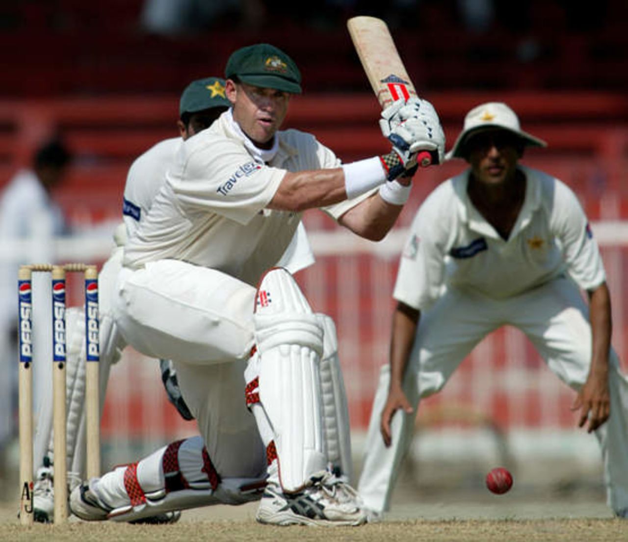 Australia's Matthew Hayden prepares for a sweeping shot as Pakistan's Younis Khan (R) watches at Sharjah's stadium October 12, 2002 on the second day of their second cricket test match. The second and third tests are being held in the neutral venue of Sharjah after Australia balked at playing in Pakistan due to security concerns.