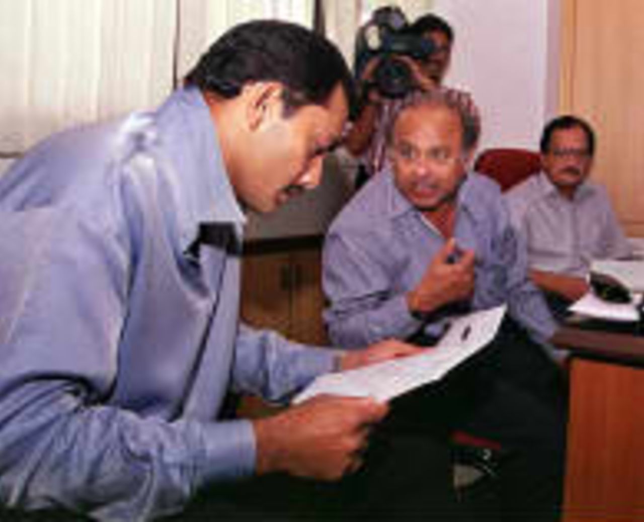 India cricket captain Mohammed Azharuddin (L) goes through the team list after the team was announced 17 November in Bombay for the forthcoming three Test series and five one-day internationals against New Zealand to be played in December and January, while Jaywant Lele (C), Secretary for the Board of Control for Cricket in India and Chairman Ajit Wadeker (R) look on.