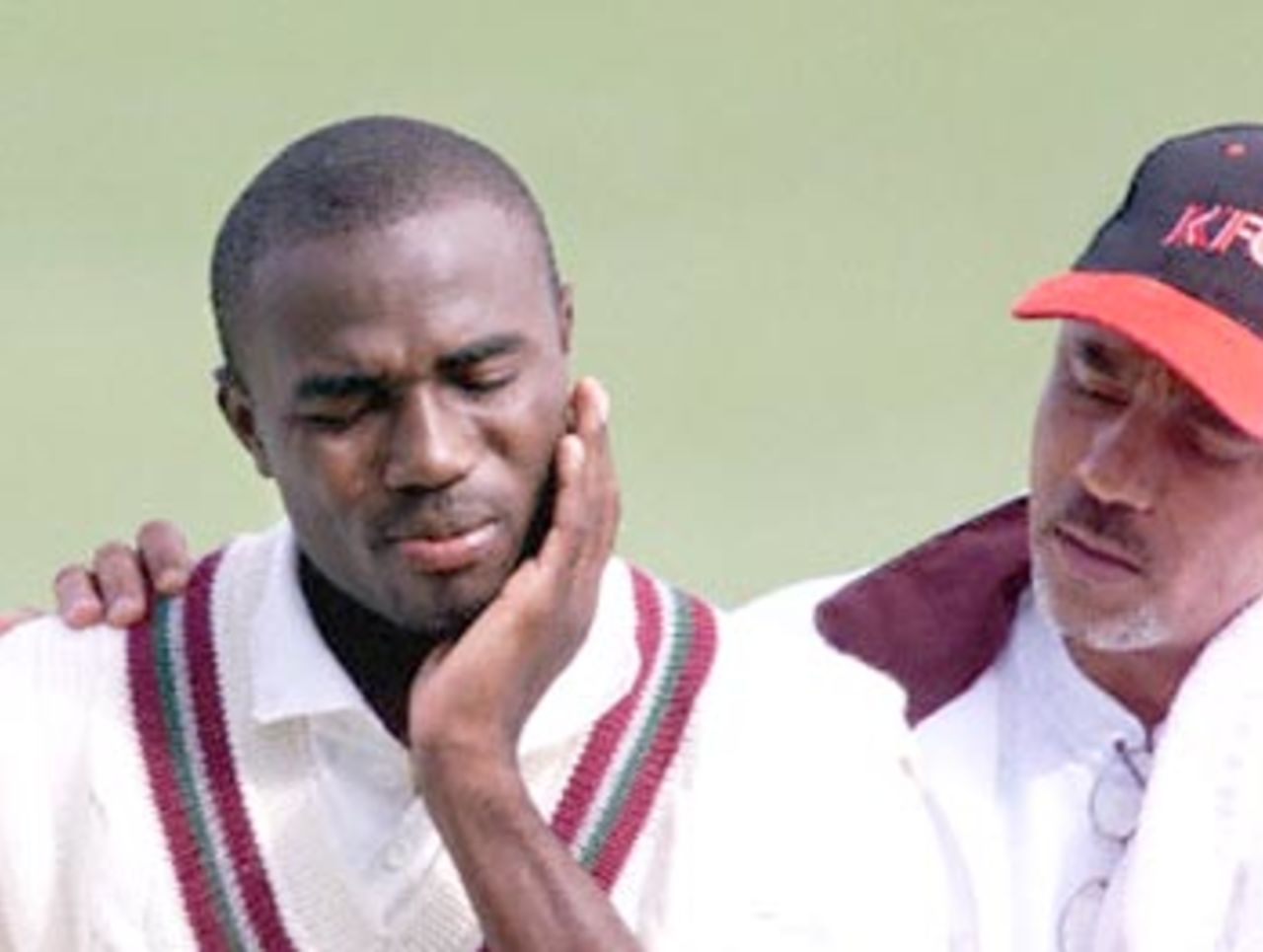 West Indies tailender Kerry Jeremy (L) holds his jaw as he walks from the WACA ground accompanied by assistant coach Jeffrey Dujon (R) during a four-day game against the Western Warriors (a West Australian state side) at the WACA ground in Perth 09 November 2000. Jeremy was hit in the face by a delivery from Matthew Nicholson and was forced to retire injured on seven runs, with the West Indies innings coming to an end on 9 for 132. He was transferred to hospital to get a cautionary X-ray for his jaw.