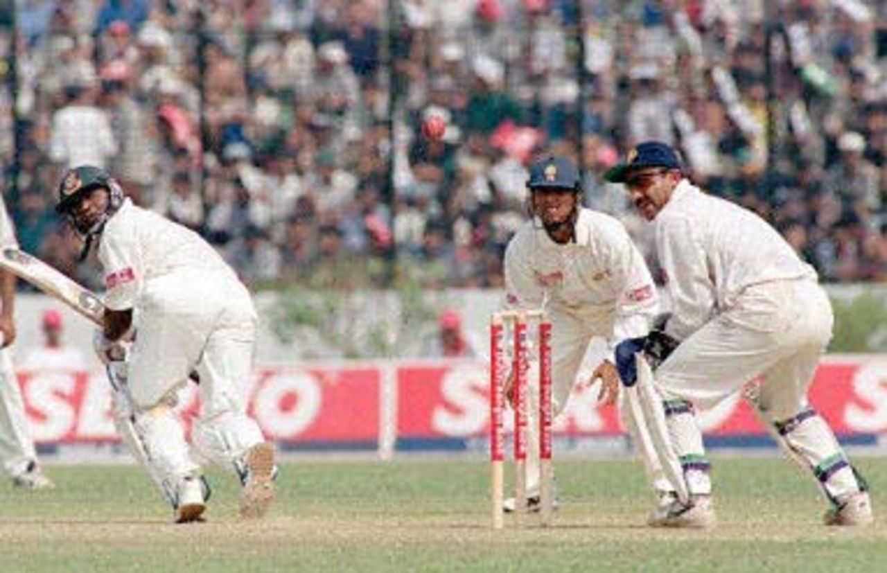 One of Bangladesh's top batsman Aminul Islam looks back after hitting a boundary off Sunil Joshi10 November 2000 at the Bangabandhu National Stadium during this South Asian country's inaugural Test match against India. Sachin Tendulker and keeper Saba Karim look on. Bangladesh won the toss and elected to bat.