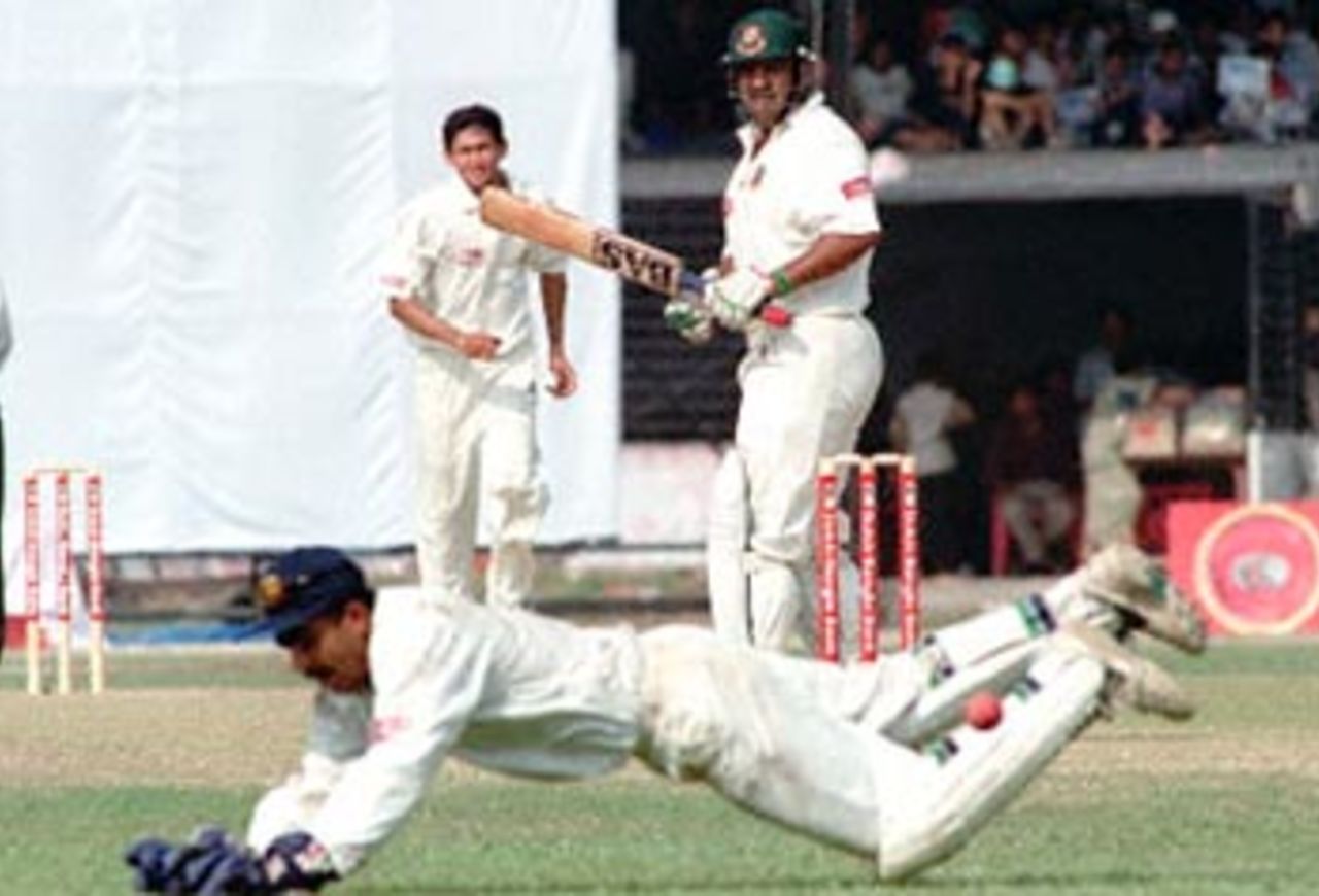 Bangladeshi bastman Akram Khan (C) and Indian pace bowler Ajit Agarkar (L) look on as wicket keeper Saba Karim jumps to stop a ball 10 November 2000 at the Bangabandhu National Stadium during this South Asian country's inaugural Test match against India. Bangladesh scored 239 for six at the end of first day in their debut match.
