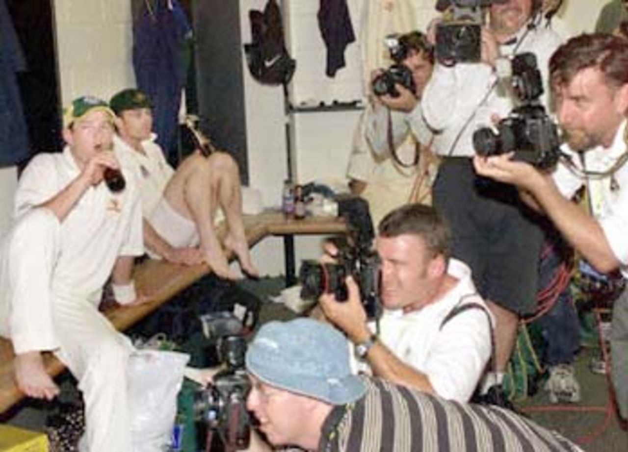 Australian batsman Mark Waugh (L), who is under intense public and media pressure over his form and a ICC inquiry into match fixing, watches the photographers capture the team celebrating after they defeated the West Indies by an inning and 126 runs, on the third day of the first Test match at the Gabba in Brisbane, 25 November 2000. The Australian victory equals the world record of eleven consecutive Test victories.