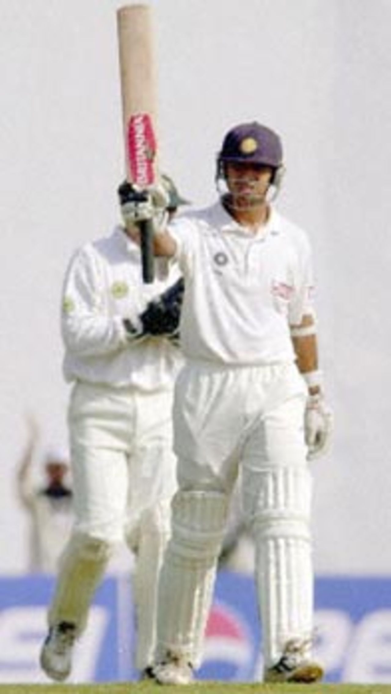 Indian batsman Rahul Dravid raises his bat to acknolwedge the cheering crowd after completing his century as Zimbabwe wicket keeper Andy Flower (behind) looks on, during the second day of the second test match between India and Zimbabwe 26 November 2000 in Nagpur. Dravid was unbeaten on 153 runs as India stood at 463 for two by lunch. India is already 1-0 up in the two-test-series against Zimbabwe.