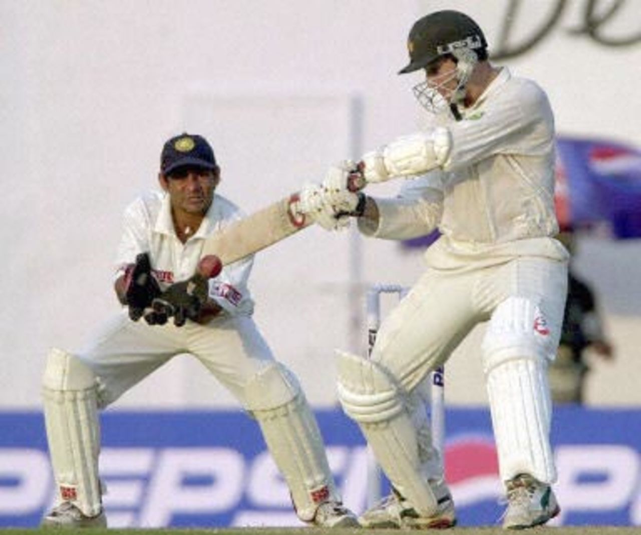 Zimbabwean batsman Guy Whittall hits a delivery from Indian spinner Sunil Joshi as Indian wicketkeeper Vijay Dahiya (L) looks on during the second day of the second Test match between India and Zimbabwe, 26 November 2000 in Nagpur. Whittall, the highest scorer for Zimbabwe, remained unbeaten at 34 as Zimbabwe scored 59 for 1 in reply to India's total of 609 runs at the end of day's play.