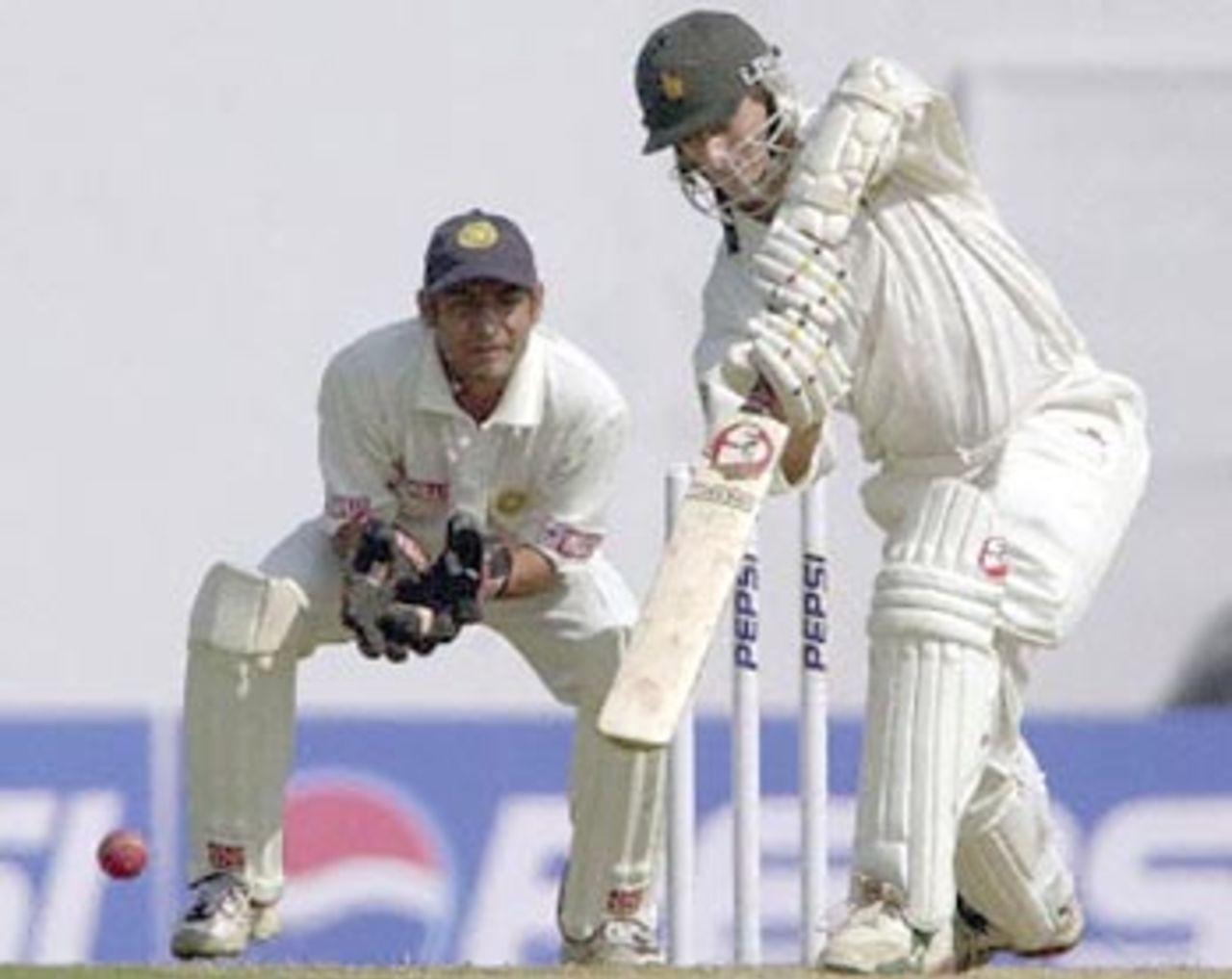 Zimbawean batsman Guy Whittall (R) drives a delivery from Indian spinner Sunil Joshi as Indian wicket keeper Vijay Dahiya (L) looks on during the third