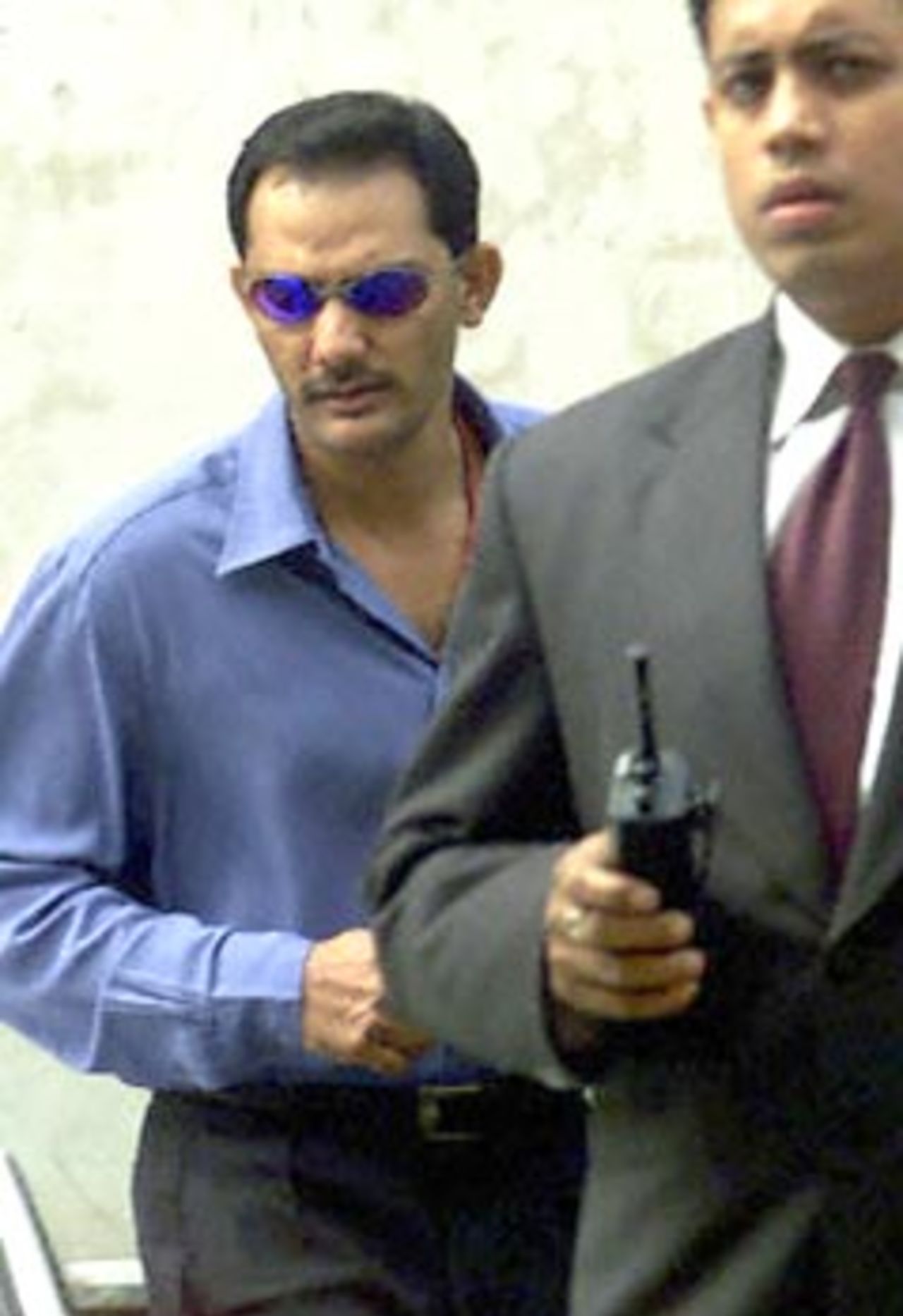 Former Indian cricket captain Mohammad Azharuddin (L) is accompanied by a security officer as  he leaves the staff entrance of the Taj Man Singh hotel following a last hearing with cricket board officials 28 November 2000. Azharuddin, could face a possible life ban for alleged match fixing.