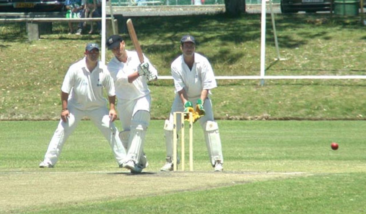 Louis du Plessis of CTCC drives the ball to the mid wicket boundary. The wicketkeeper is Peter Stewart and the slip fielder is Derrick Lane.