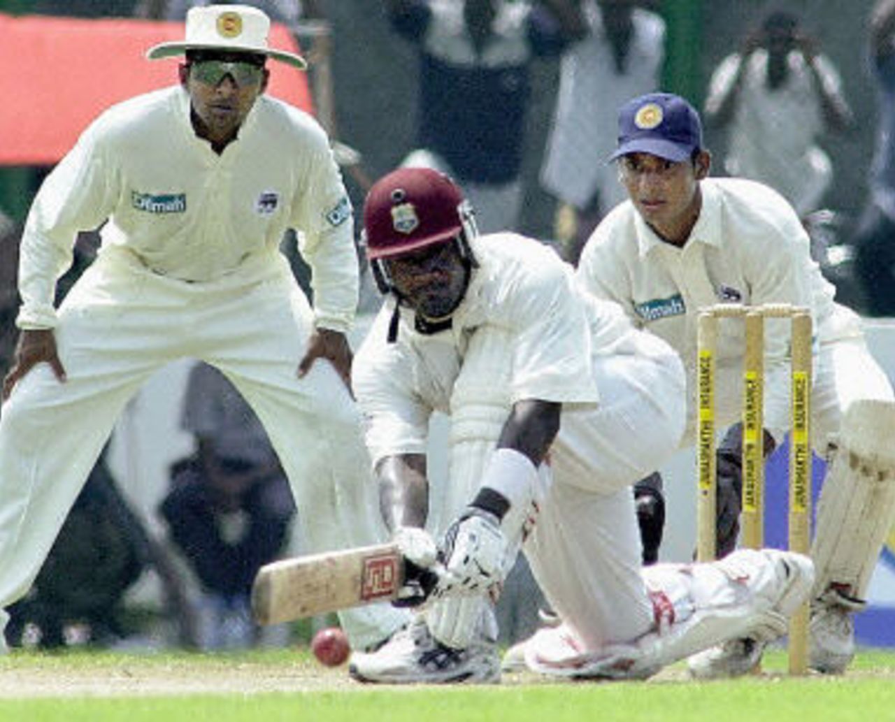 West Indies skipper Carl Hooper sweeps a ball as Mahela Jayawardena and wicketkeeper Kumar Sangakkara looks on during the Second day of the first cricket test match between Sri Lanka and West Indies, 14 November 2001