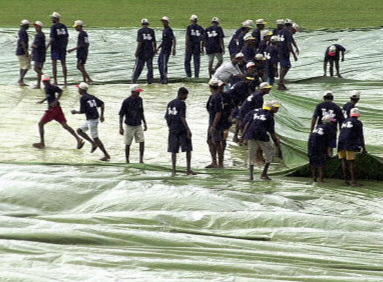 Ground staff cover the pitch during the first day of the second cricket Test match between Sri Lanka and West Indies at the Asgiriya Stadium in Kandy