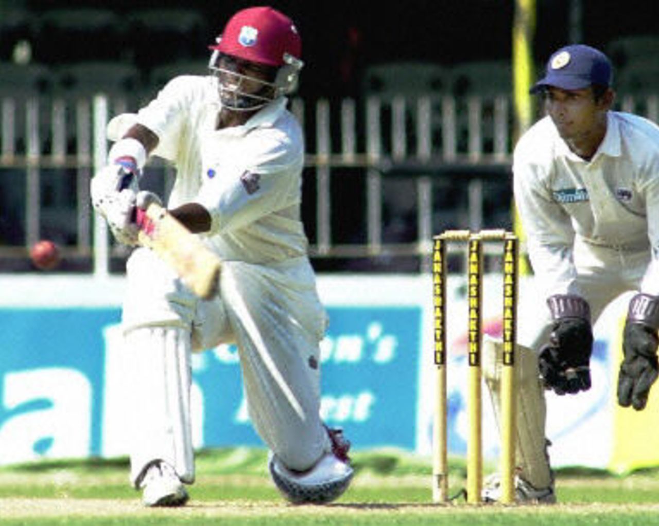 Brian Lara sweeps a ball to the boundary for four as wicketkeeper Sangakkara looks on