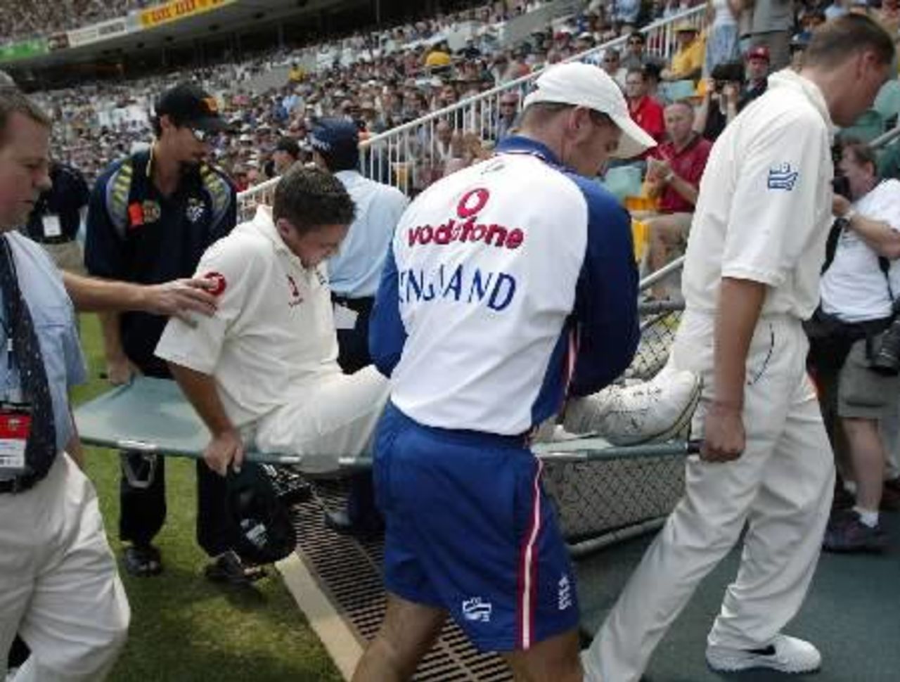 Australia paceman Jason Gillespie (2nd L) helps carry Simon Jones off the field after the England fast bowler injured his knee fielding on the opening day of the first Ashes test in Brisbane.