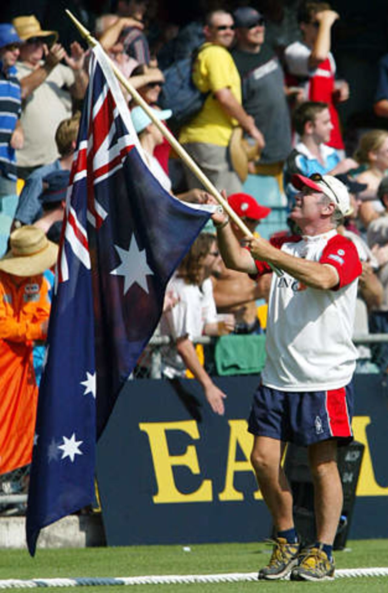 Former Australian captain Allan Border carries an Australian flag as he walks around the Gabba during the first day's play in the first Ashes test match in Brisbane November 7, 2002. Border was finishing a 1000 kilometre (621 mile) walk from Sydney to Brisbane raising money for charity, after being inspired by former England player Ian Botham's similar deed.