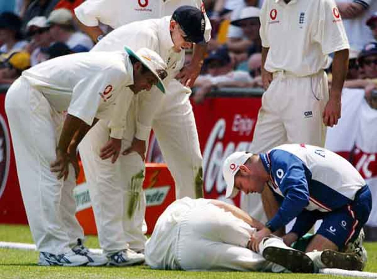 England's Simon Jones (C) is attended to by a team medic after injuring his knee while fielding during the first day's play in the first Ashes test match at the Gabba in Brisbane November 7, 2002.