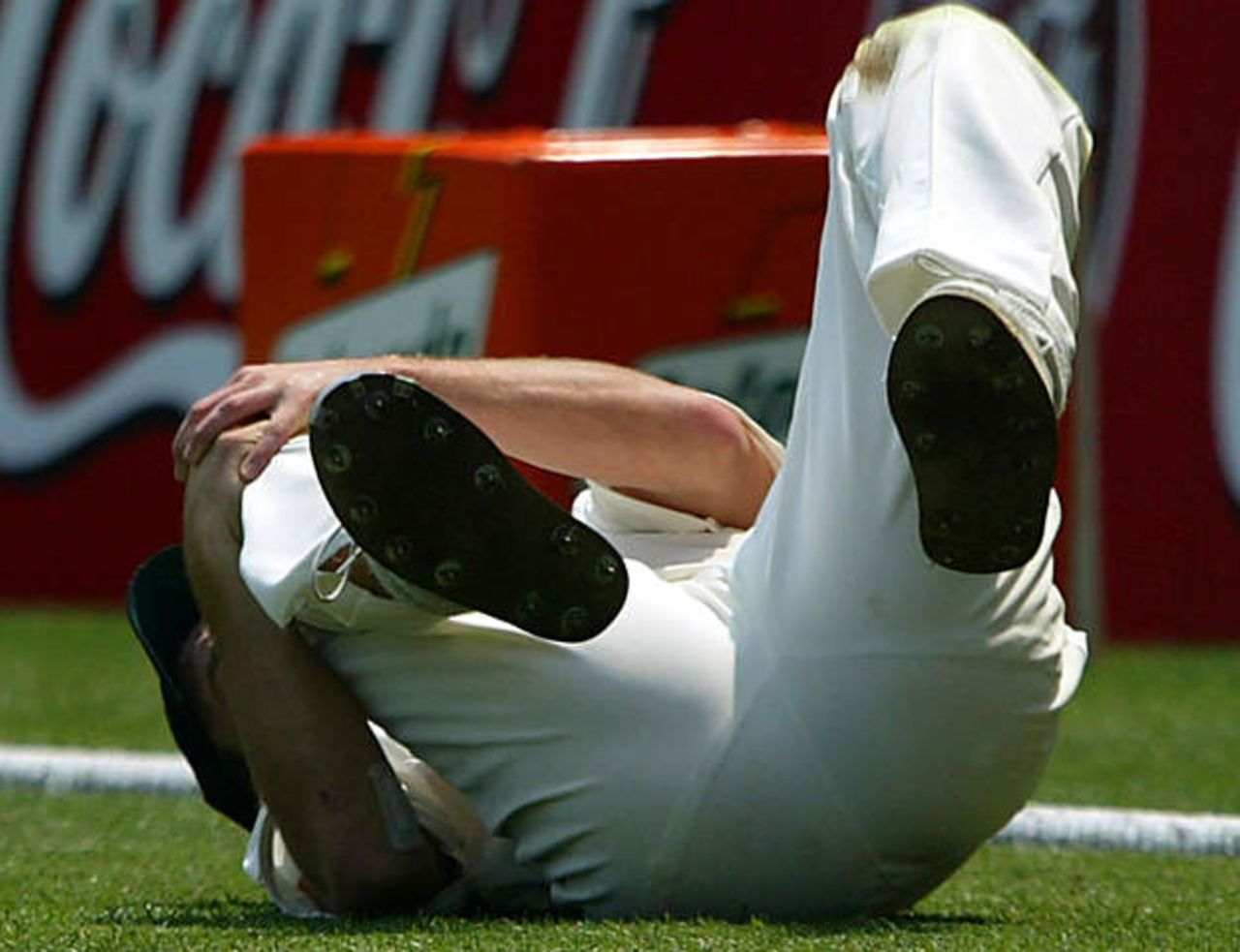 England's Simon Jones lies on the ground after injuring his knee while fielding during the first day's play in the first Ashes test match at the Gabba in Brisbane November 7, 2002.