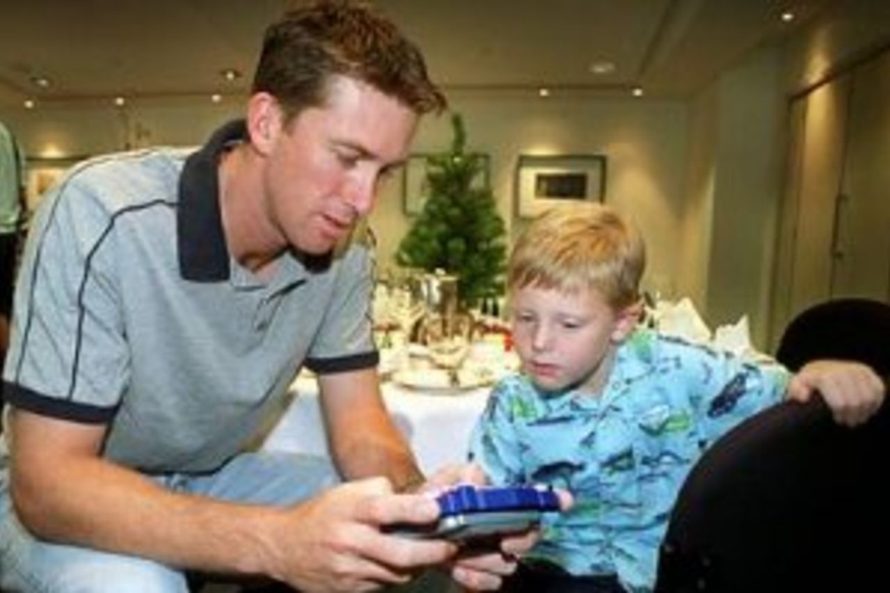 25 Dec 1999: Australian cricket team fast bowler Glenn McGrath plays gameboy with team fitness advisor David Misson's son, Conor, during the Australian team's Christmas lunch at their team hotel this morning. Tommorrow Australia play India at the Melbourne Cricket Ground, Melbourne, Australia, in the Boxing Day Test Match.