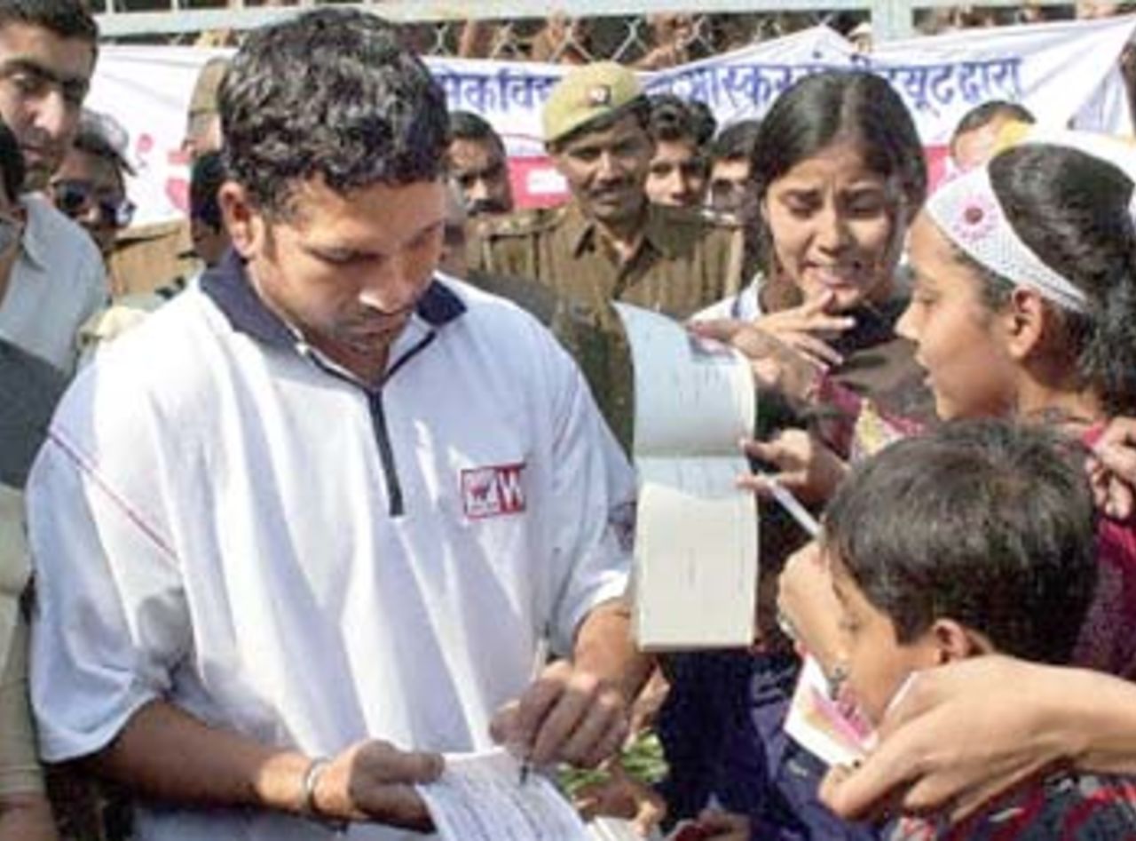 India's star batsman Sachin Tandulkar (L) signs autographs for children 10 December 2000 during the practice session on the eve of the fourth one day cricket match between India and Zimbabwe in Kanpur. India leads the five-match series 2-1.