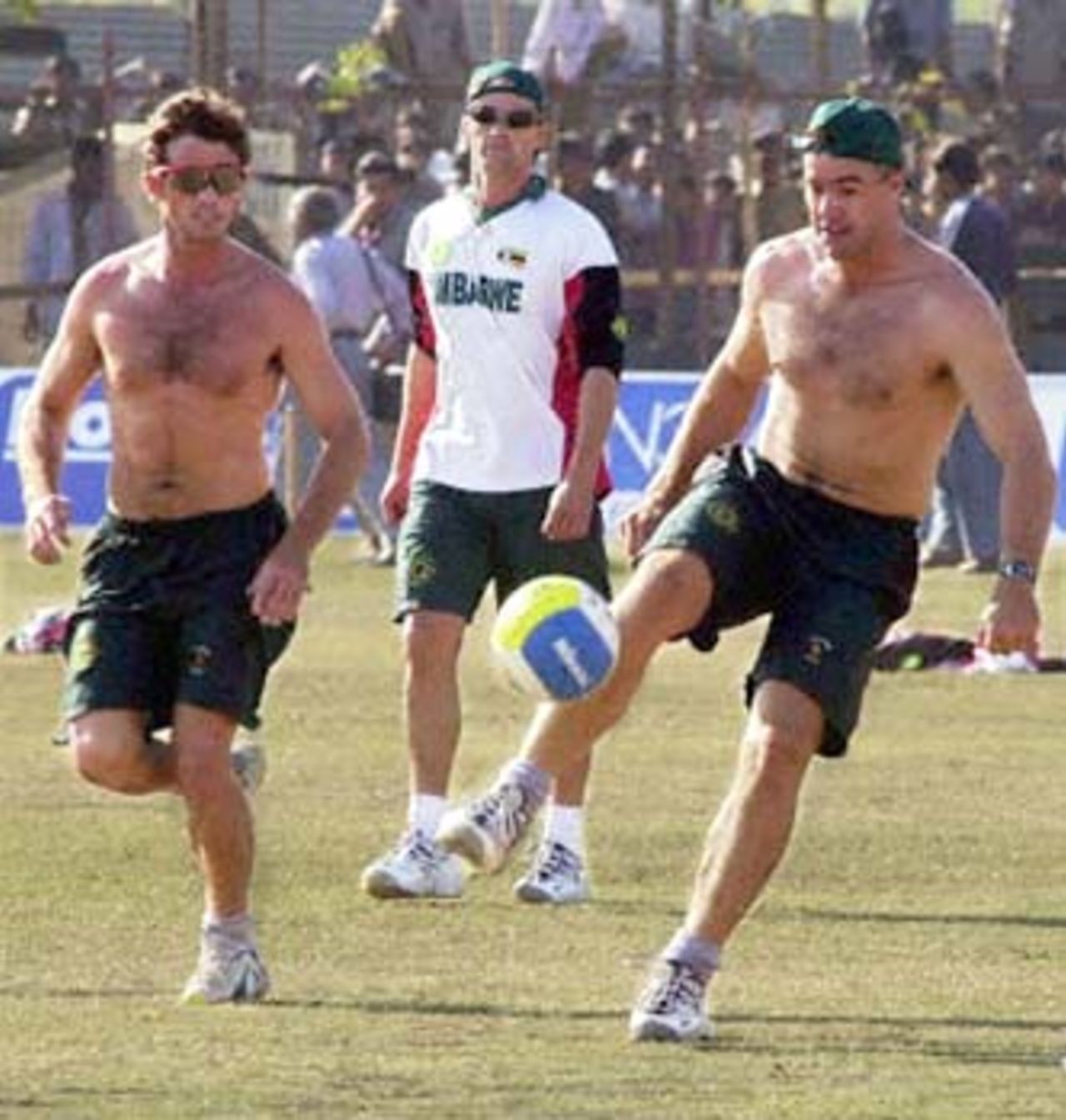Zimbabwe cricket team skipper Heath Streak (R) plays football with team member Guy Whittall (L) during practice 13 December 2000, ahead of the final one-day International cricket match against India at the Municipal cricket stadium at Rajkot. India leads with an insurmountable 3-1 ahead of the 14 December final Test. Man at center is unidentified.